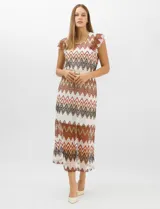 Vestido midi confeccionado en tejido de punto calado, con patrón geométrico en zigzag en tonos blanco, marrón, tostado y azul. Presenta escote a la base, mangas cortas con volados en los hombros, silueta recta y forro interior a tono. Incluye un cinturón fino con hebilla metálica.