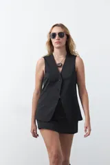 Chaleco sastrero de color marrón, con silueta recta, escote en V y cierre frontal con botones. Presenta una estructura definida y tejido con caída firme.