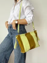 Cartera tipo sobre de cuero con diseño de rayas verticales en tonos verde menta y marrón tostado. Cuenta con detalles de borlas colgantes en los laterales.