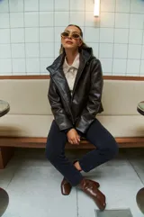 Campera marrón de cuero sintético con cierre frontal asimétrico y cuello con solapa.