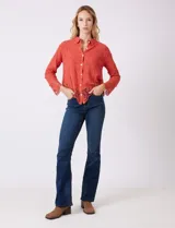 Camisa de algodón con bordado suizo, cuello con solapa y cierre frontal con botones. Presenta mangas largas con terminación de encaje calado y un ruedo asimétrico en pico con un amplio galón de encaje.