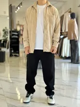 Sobrecamisa de pana color beige, de manga larga, con cuello clásico, cierre frontal de botones y un bolsillo aplicado en el pecho.