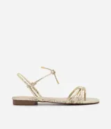Sandalia plana marca Satinato, color dorado metalizado con textura tipo croco. Posee tiras finas con detalle de nudo en el empeine y cierre de lazo ajustable al tobillo. Diseño de puntera redonda y suela plana.