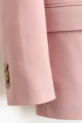 Blazer cruzado rosado con solapas de pico, hombreras y bolsillos delanteros con solapa. Cuenta con cierre de doble botonadura y forro interior.