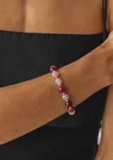 Pulsera elástica de piedras naturales de ágata en tonos rosados y borravino, intercaladas con pequeños separadores dorados.