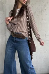 Remera de manga larga a rayas horizontales en tono tostado y blanco, con cuello redondo y cartera de botones frontal.