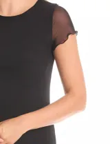 Vestido midi negro con cuello redondo, mangas cortas de microtul transparente y ruedo con acabado roulette. Presenta un forro interno opaco y una capa exterior de microtul, con un tajo lateral profundo.