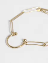 Pulsera plateada de eslabones con dije de medio círculo.