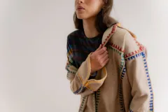 Chaqueta gris de paño de lana con detalles de crochet rojo, corte cuadrado y cuello camisero.