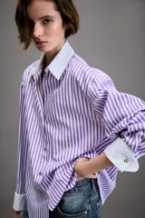 Camisa de manga larga con cuello solapa y puños en contraste color blanco. Presenta un diseño de rayas verticales en color lila y blanco, con cierre frontal de botones.