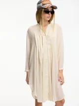 Túnica o camisa larga color blanco hueso, confeccionada en algodón, con cuello mao, frente abotonado y pliegues verticales en el pecho.