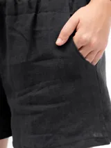 Short de lino color negro, con cintura elástica y bolsillos laterales, de diseño holgado y cómodo.