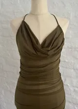 Vestido corto de microtul color verde oliva, con escote drapeado, espalda descubierta y breteles finos. Presenta un diseño ajustado con frunces laterales en toda la prenda.