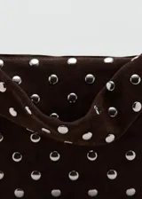 Bolso de mano tipo baguette de cuero marrón, adornado con tachas metálicas plateadas dispuestas en todo su diseño, incluyendo la correa.