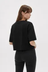 Remera negra de algodón de corte ancho y corto, con mangas cortas y cuello redondo a la base.