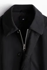 Campera de sarga levemente acolchada con cuello inglés, cierre frontal y solapa con botones. Presenta mangas raglán, bolsillos insertados delanteros, un bolsillo interior y cordón ajustable en el bajo.