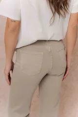 Pantalón de jean color arena, de corte flare con pierna levemente acampanada y tiro medio. Cuenta con cierre frontal, botón, pasacintos y bolsillos funcionales.