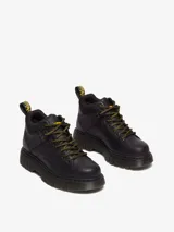 Borcegos Dr. Martens modelo Woodard de cuero negro, con diseño de montaña, cuello acolchado, suela acanalada Club Wedge y cordones estilo excursionista en negro y amarillo.