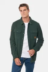 Camisa azul marino de poliéster con textura polar, corte recto, cuello camisero, cierre frontal con botones a presión, dos bolsillos de parche con solapa abotonada en el pecho y puños abotonados.