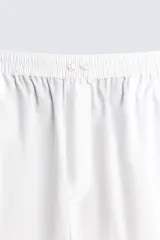 Pijama de dos piezas confeccionado en popelín de algodón blanco, con vivos de ribete en color bordó. Incluye una camisa de manga larga con cuello bowling, bolsillos de plastrón y cierre frontal de botones, y un pantalón de corte relajado con cintura elástica y bolsillos laterales.