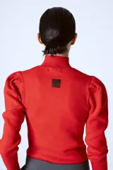 Polera de punto color rojo, con cuello alto y mangas largas con detalle de frunces en los hombros.