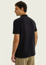 Chomba negra de manga corta con cuello camisero, cartera de botones y detalle bordado en el pecho.