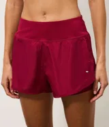 Short runner deportivo 2x1 de microfibra color bordó, con cintura elástica, bolsillo funcional con cierre y bajo redondeado.