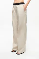 Pantalón de gabardina color beige, de corte recto, tiro medio-bajo, fit oversize y cintura elastizada con logo de la marca.