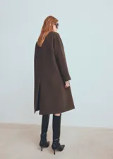 Abrigo de corte sastre con diseño de doble botonadura y solapas amplias. Presenta un estampado de cuadros pequeños en tonos marrones y oscuros, con una silueta estructurada y elegante.