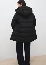 Chaqueta puffer acolchada color negro, con diseño recto, cuello alto y capucha. Cuenta con manga larga con puños elásticos, bolsillos laterales con cierre de cremallera y cierre frontal de cremallera doble. Incorpora acabado repelente al agua.