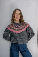 Sweater de punto con diseño jacquard en la zona del cuello y hombros. Presenta un patrón geométrico en tonos rosado y naranja sobre una base de color gris jaspeado. Posee cuello redondo, manga larga y un corte holgado.