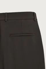 Pantalón relaxed fit marrón oscuro, de corte ancho y recto, con pliegues frontales, bolsillos laterales y cierre con botón y cremallera.