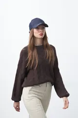 Sweater tramado color marrón oscuro, de diseño clásico con textura en relieve que forma un patrón geométrico. Tiene cuello redondo y mangas largas.