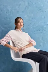 Chaleco de tejido de punto color beige claro, con cuello redondo y diseño de líneas limpias con hombros caídos y terminaciones acanaladas.