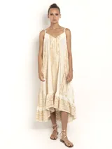 Vestido midi blanco con breteles finos y escote en V. Presenta un corte amplio y fluido con bordados geométricos en hilo dorado, y un ruedo con volado.