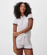 Short de pijama femenino confeccionado en tejido peach touch de poliéster, con cintura elastizada, botones frontales y encaje bordó en los bajos. Presenta un estampado geométrico con pequeños corazones en tonos blancos y oscuros.
