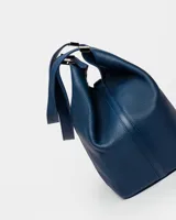 Bolso de hombro azul marino de cuero graneado con logo grabado en el centro.