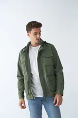 Campera de gabardina verde militar con capucha desmontable y ajustable, cierre frontal con cremallera y múltiples bolsillos con solapa.