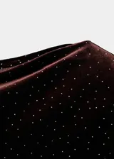 Vestido corto entallado de terciopelo marrón con aplicaciones de brillos, cuello asimétrico de un solo hombro y manga larga.