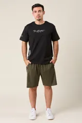 Bermuda deportiva color verde militar, de corte suelto, confeccionada en nylon. Cuenta con cintura elástica, cordón de ajuste, detalles de líneas en los costados y bolsillos con cierre.