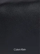 Cartera bandolera Calvin Klein modelo Camera, color negro con textura granulada y logo de la marca en el frente. Tiene correa de cadena plateada y cierre superior con cremallera.