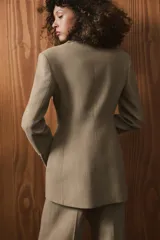 Blazer entallada de Zara Woman Collection, confeccionada en tejido con lana. Presenta cuello con solapas de muesca, cierre frontal cruzado con botones y manga larga con detalle de botones en los puños.
