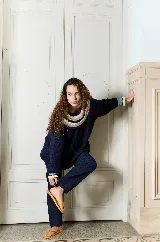 Buzo de punto bordó estilo oversize, con cuello babero amplio con volados y franjas en tonos amarillo y rojo, manga larga con terminación en volados.