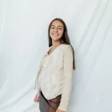 Chaleco corto con estampado abstracto en tonos dorados y azules, escote en V y cierre frontal con botones de madera.