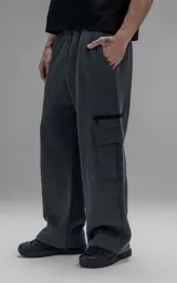 Pantalón tipo jogger gris melange de corte baggy y silueta amplia, confeccionado en frisa de algodón. Presenta cintura elástica, bolsillos laterales de mano y bolsillos estilo cargo con solapa y cierre en los laterales.
