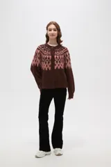 Cardigan de tejido jacquard con diseño geométrico en la parte superior, cuello redondo y cierre frontal con botones. Presenta un corte holgado y mangas largas con puños acanalados.