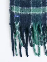 Bufanda de estilo escocés con textura suave, diseño a cuadros en tonos azul y verde, con flecos en los extremos.