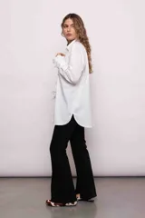 Camisa blanca de algodón con cuello clásico, cierre frontal con botones, mangas largas con puños abotonados y volados en el frente y los puños.