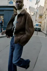 Chaqueta de cuello solapa y manga larga, con diseño de doble faz que combina tejido efecto ante y borreguillo. Cuenta con cierre frontal de botones y bolsillos delanteros.