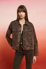 Campera de jean con lavado oscuro rojizo/marrón, estilo trucker. Presenta tachas doradas a lo largo de los bordes de los bolsillos, el canesú y los puños. Posee un bordado en relieve de diseño floral en la manga.